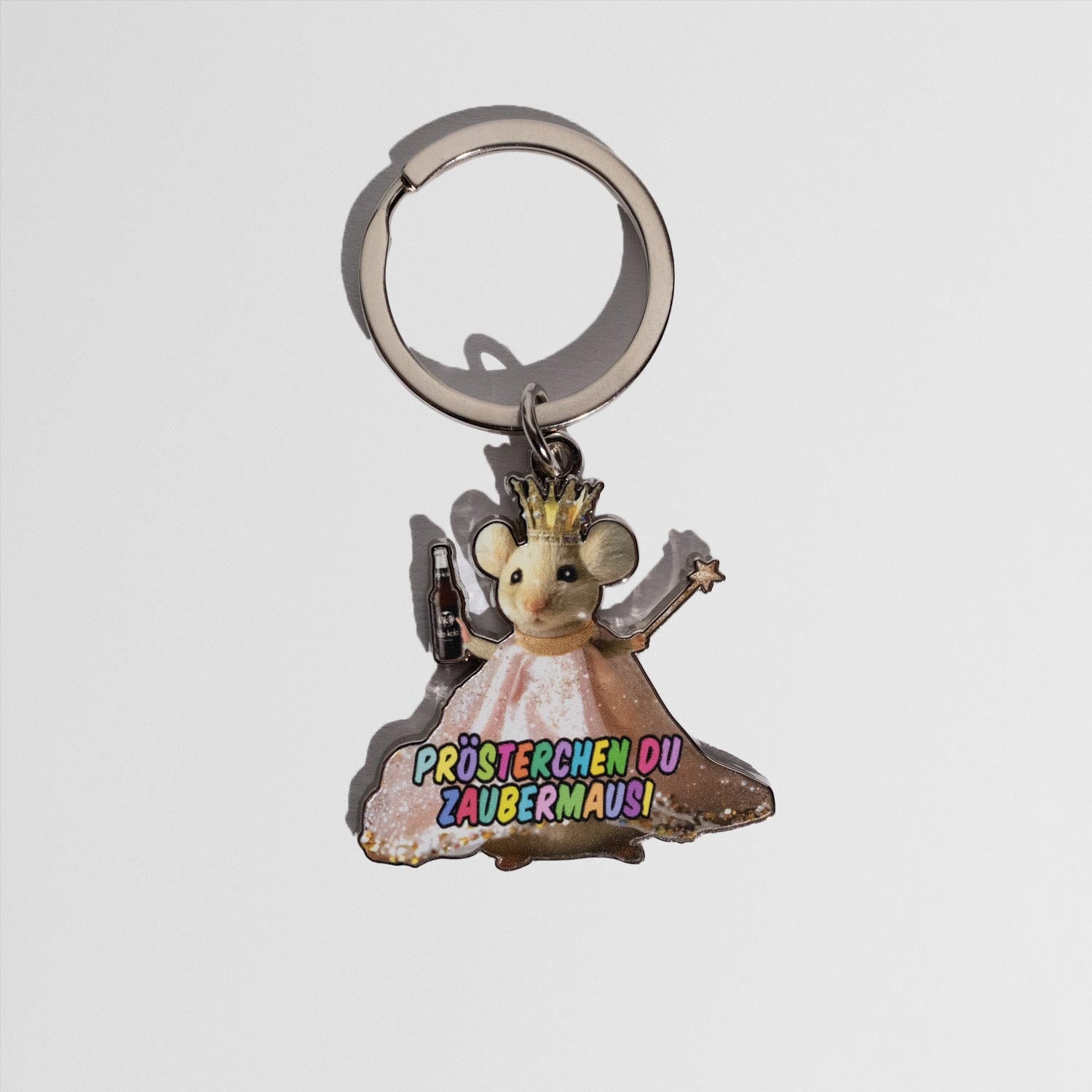 Schlüsselanhänger in Form einer Maus mit goldener Krone und rosa Kleid. Die Maus hält eine kleine Flasche in der linken Hand und einen Sternstab in der rechten. Auf dem Kleid steht in bunten Buchstaben: ‚Prösterchen du Zaubermausi‘.