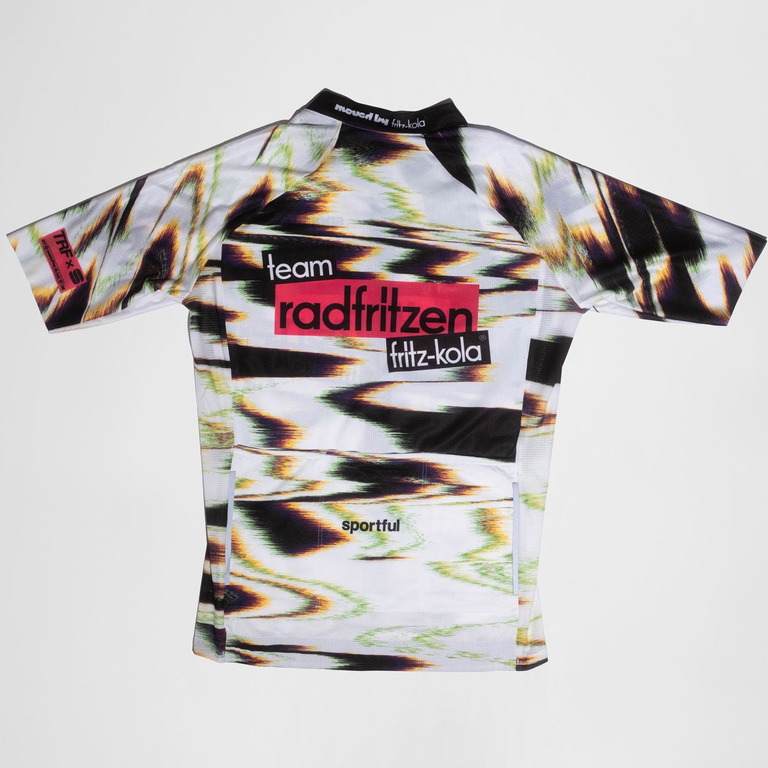 Rückseite Weißes Radtrikot mit abstraktem Farbverlauf-Muster in Grün, Pink und Schwarz. Zentraler roter Balken mit "radfritzen" auf der Brust, darunter "fritz-kola" Logo. Kurze Ärmel.
