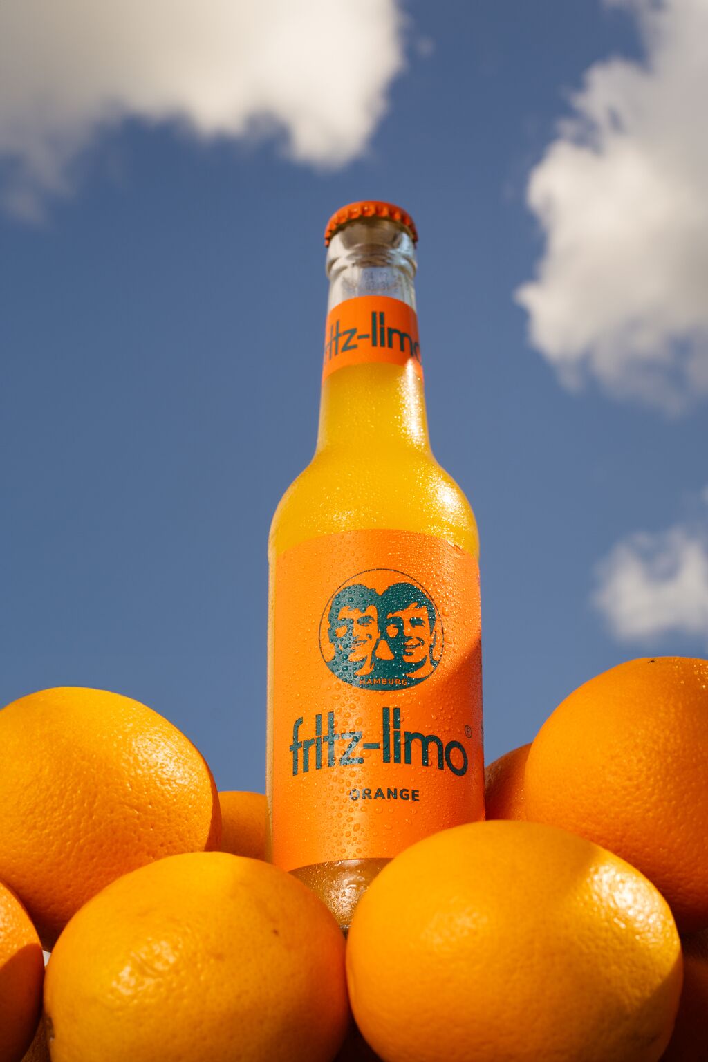 fritz-limo orange 0,33 l mit orangen vor einem Himmel